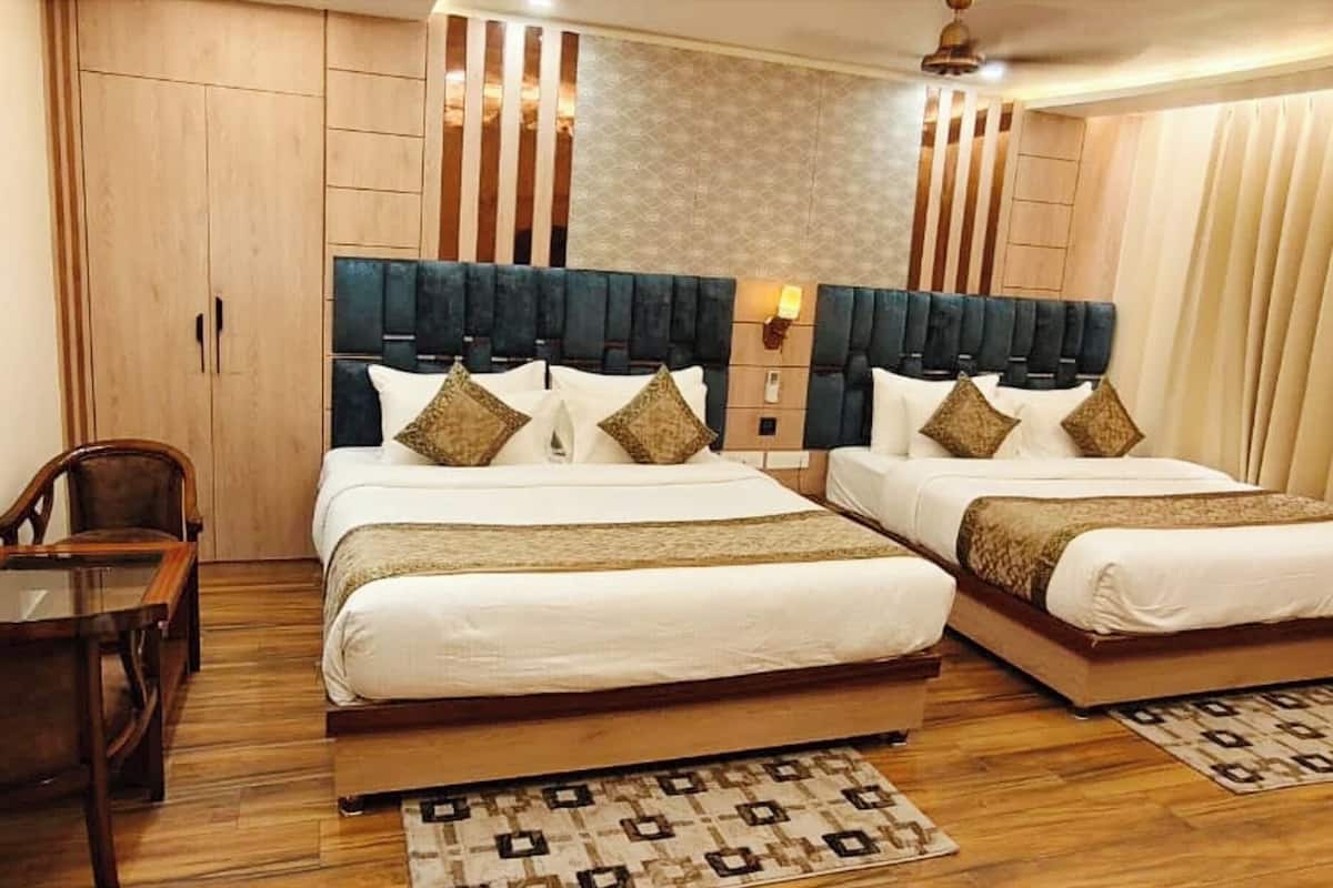 A double room with two beds, a wooden wardrobe, a small table, and a patterned rug.