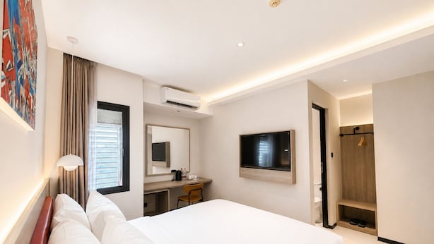 Ein Hotelzimmer mit Bett, Schreibtisch, Stuhl, Fernseher und Dusche.