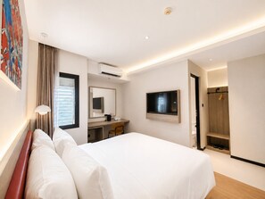 A hotel room with a bed, a desk, a chair, a television, and a shower area. - SHANKEE Hotel Melawai Blok M Jakarta (Jakarta)