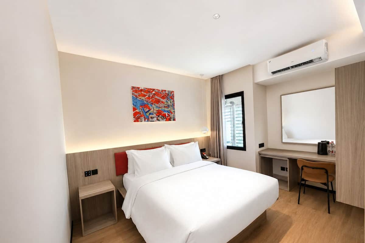 Una camera d'albergo con un letto, una scrivania, una sedia e un condizionatore d'aria.