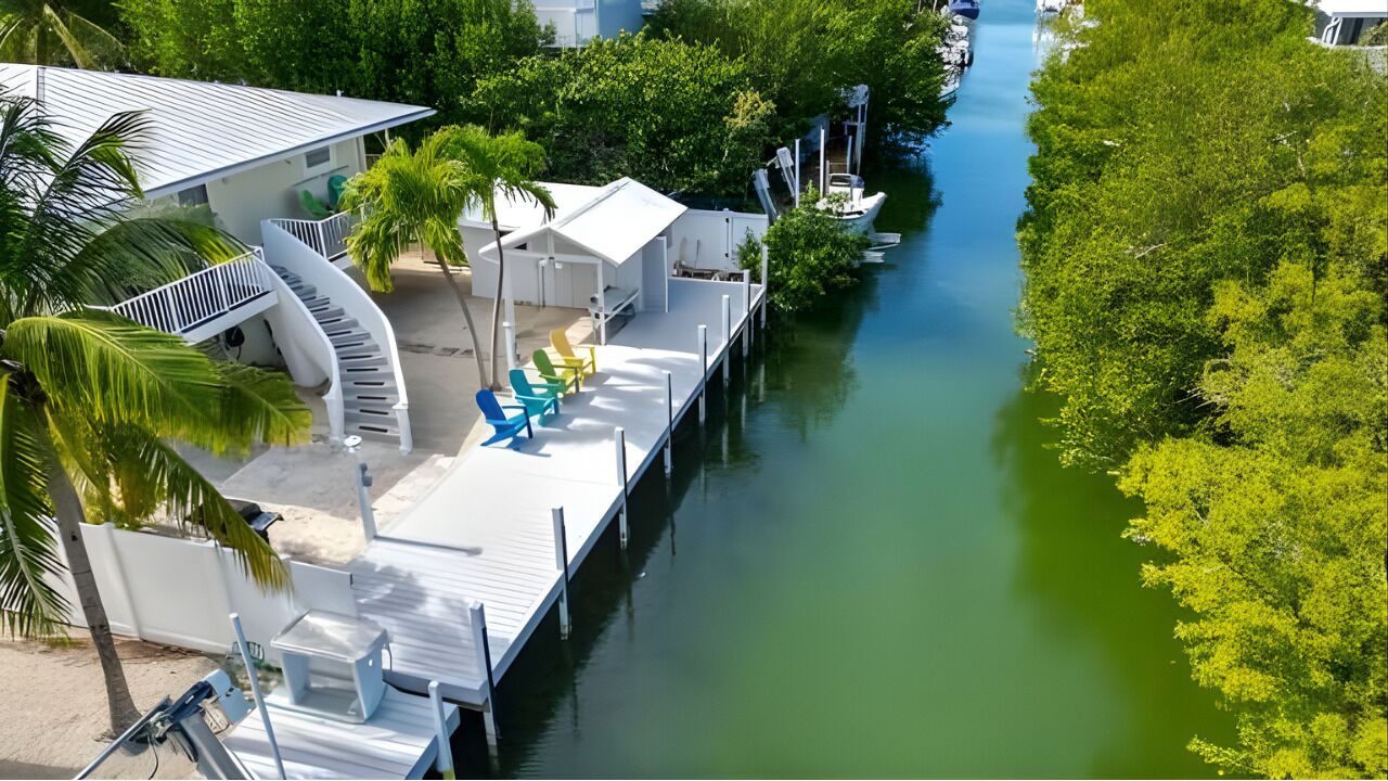 A waterfront property with a dock, lounge chairs, and a boat.