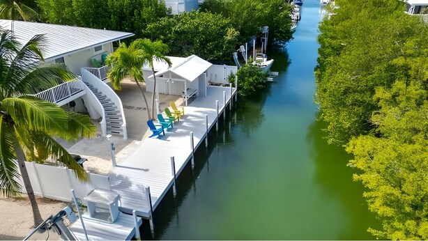 A waterfront property with a dock, lounge chairs, and a boat. - Kraken's Cove: 4‑bedroom Ramrod Key escape, minutes from open water (Summerland Key)