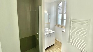 Een badkamer met een douche, een wastafel en een raam.