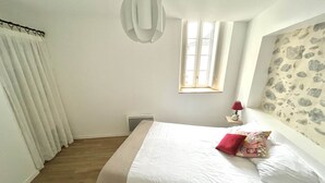 Een slaapkamer met een bed, een raam, een radiator en een muur met een stenen patroon.