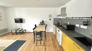 Een kleine keuken met een houten eettafel, een koffiezetapparaat en een magnetron.