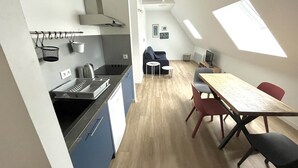 Een compacte keuken met moderne apparatuur, een eethoek met een houten tafel en stoelen, en een slaapvide met dakraam.
