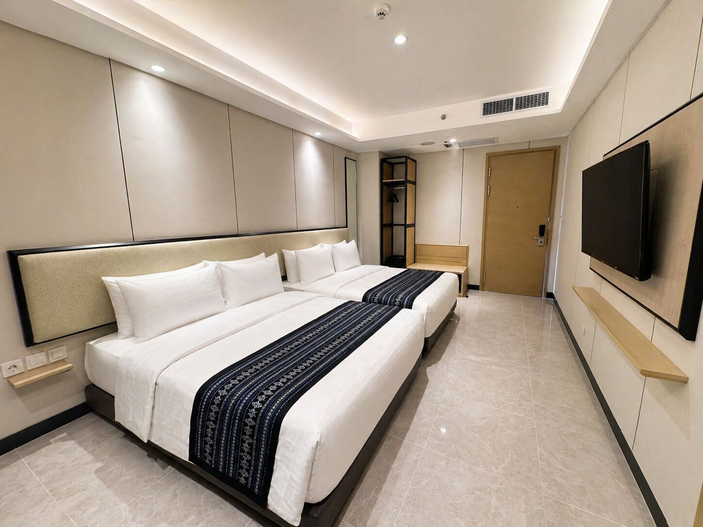 Een hotelkamer met een groot bed, een aan de muur bevestigde televisie en een deur naar de badkamer.