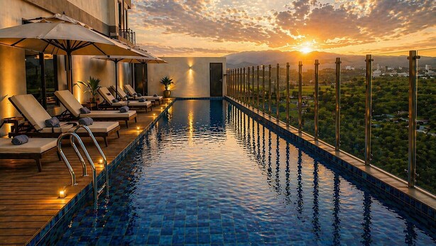 A rooftop infinity pool with lounge chairs and umbrellas, overlooking a cityscape at sunset. - Prime Plaza Hotel Mataram (Mataram)