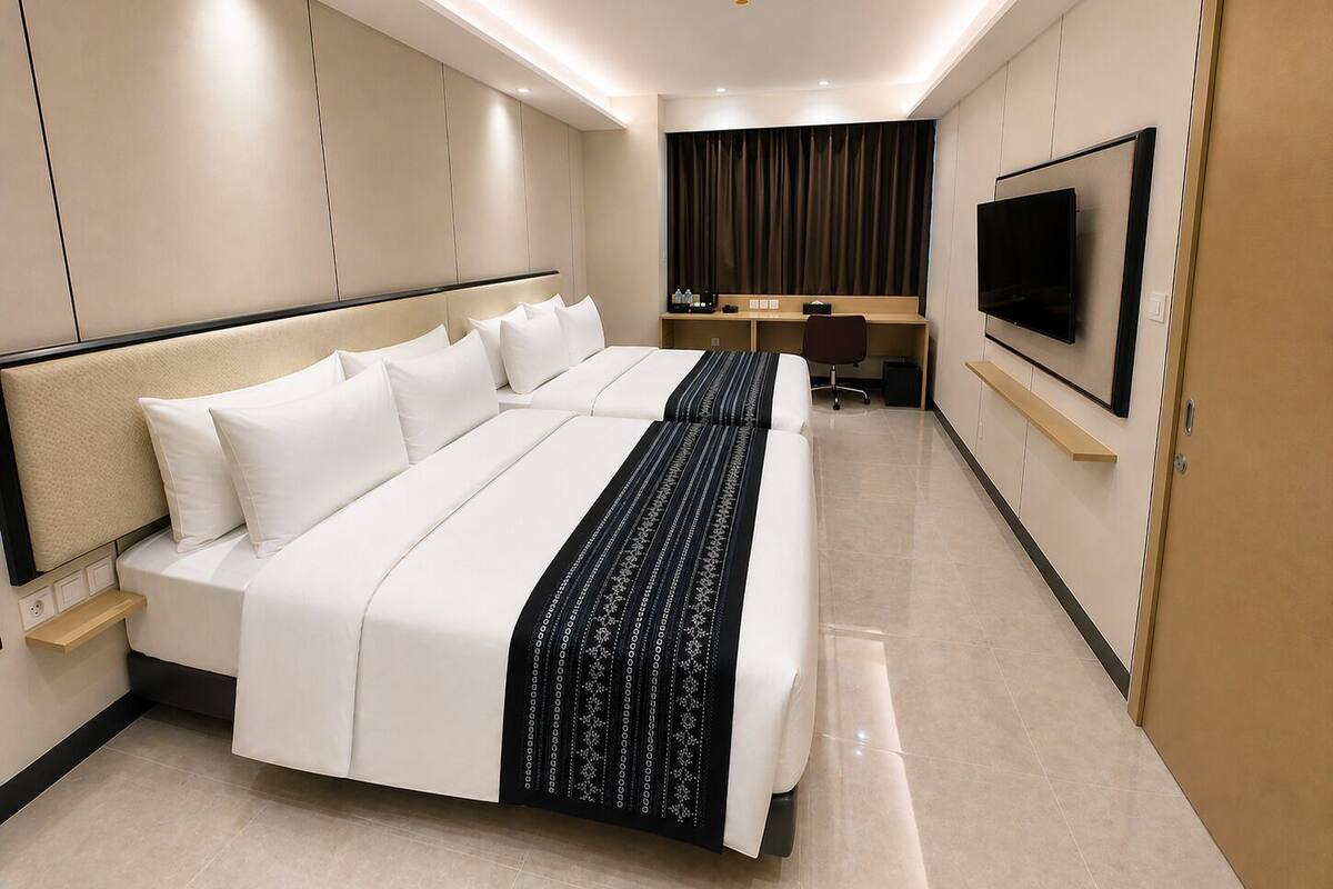 A modern hotel room with a large bed, a desk, a chair, a flat-screen TV, and a wardrobe.