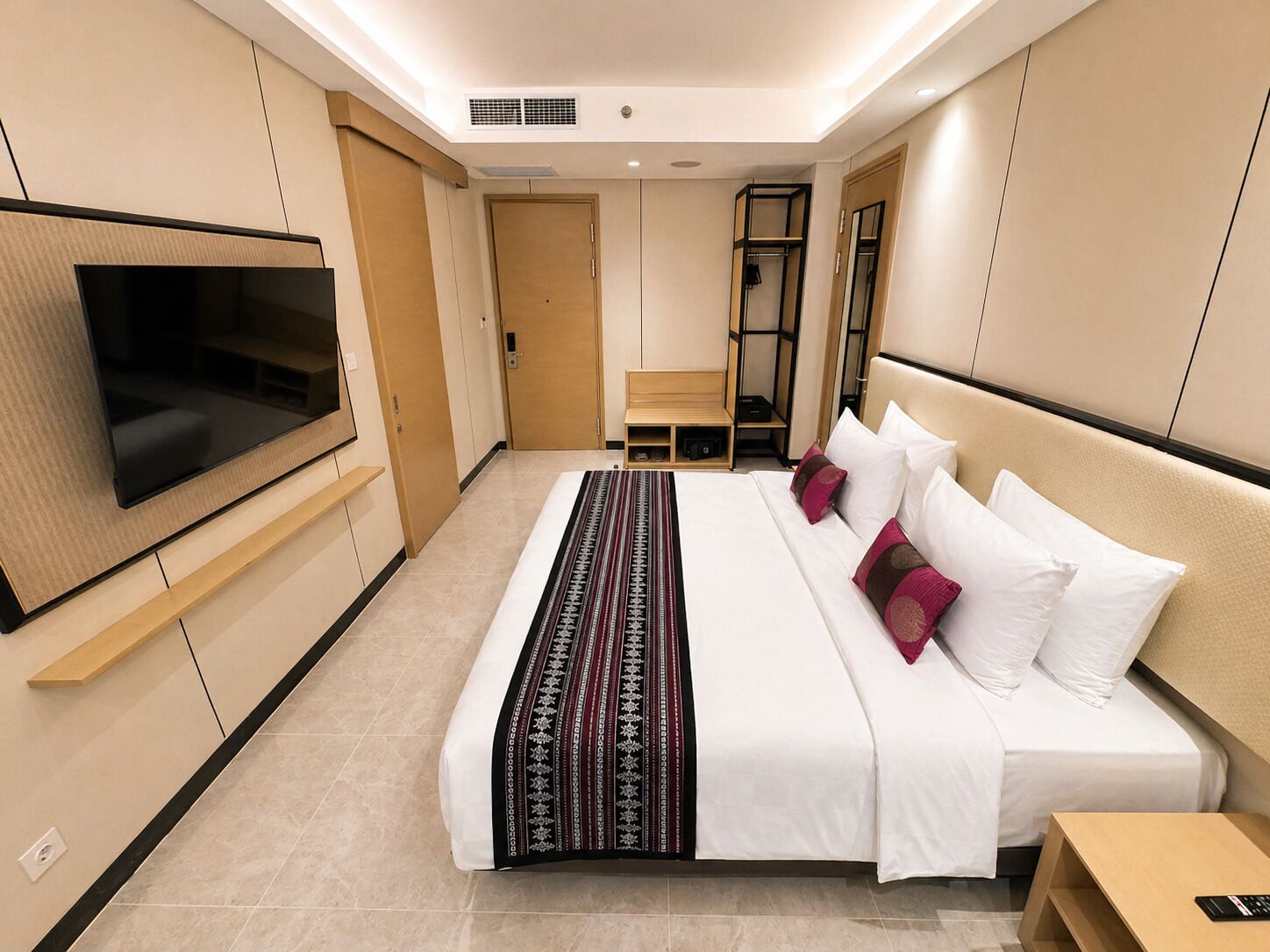 Une chambre d’hôtel équipée d’un lit, d’une télévision, d’une armoire et d’un petit coin salon.