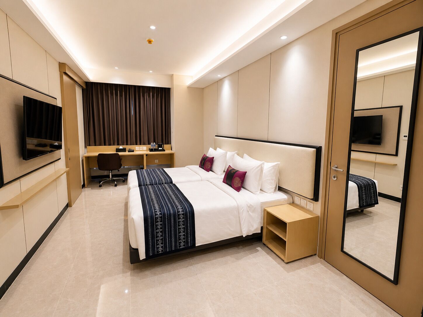 A modern hotel room with a large bed, a desk, a chair, a television, and a mirror.