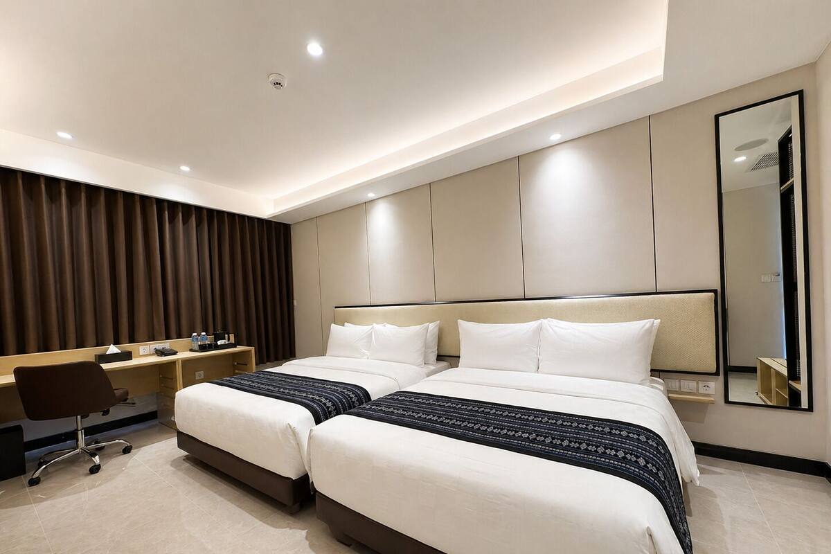 A hotel room with two beds, a desk, a chair, and a large mirror.