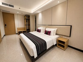 Una habitación de hotel moderna con una cama grande, mesitas de noche, un armario y una zona de estar.