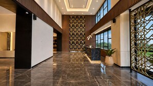 A modern lobby with a marble floor, a reception desk, and a patterned wall. - Prime Plaza Hotel Mataram (Mataram)