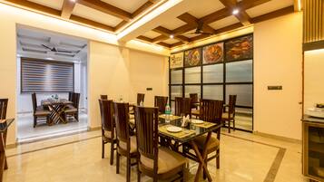 A dining area with a high ceiling, wooden beams, and a large window with a menu display.