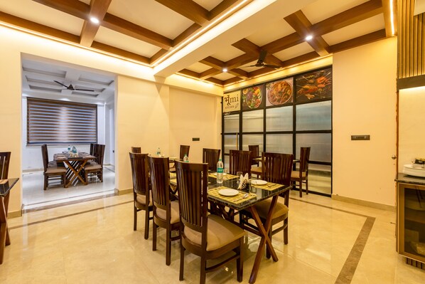A dining area with a high ceiling, wooden beams, and a large window with a menu display. - Yashobhoomi Hostel (New Delhi)
