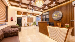 A reception area with a modern design, including a reception desk, seating area, and a chandelier. - Yashobhoomi Hostel  (New Delhi)