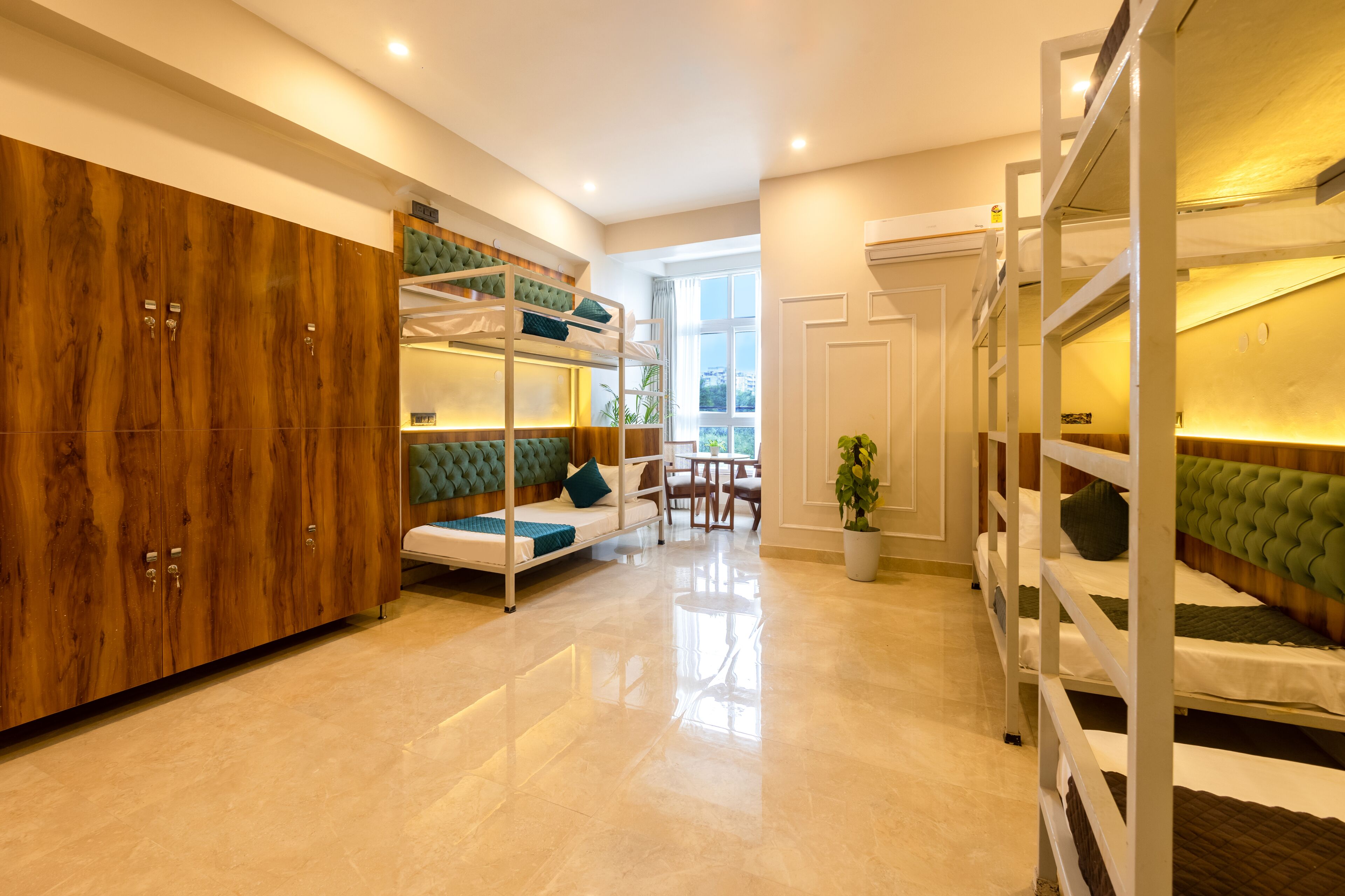A modern room with bunk beds, a wooden wardrobe, and a seating area with a table and chairs.