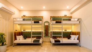 A room with two bunk beds, a potted plant, and a wooden accent wall. - Yashobhoomi Hostel  (New Delhi)
