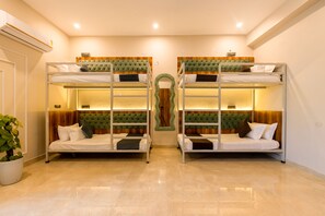 A room with two bunk beds, a potted plant, and a wooden accent wall. - Yashobhoomi Hostel  (New Delhi)