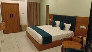 Une chambre d’hôtel avec un lit en bois, une table de chevet, une chaise, une armoire et un rideau.