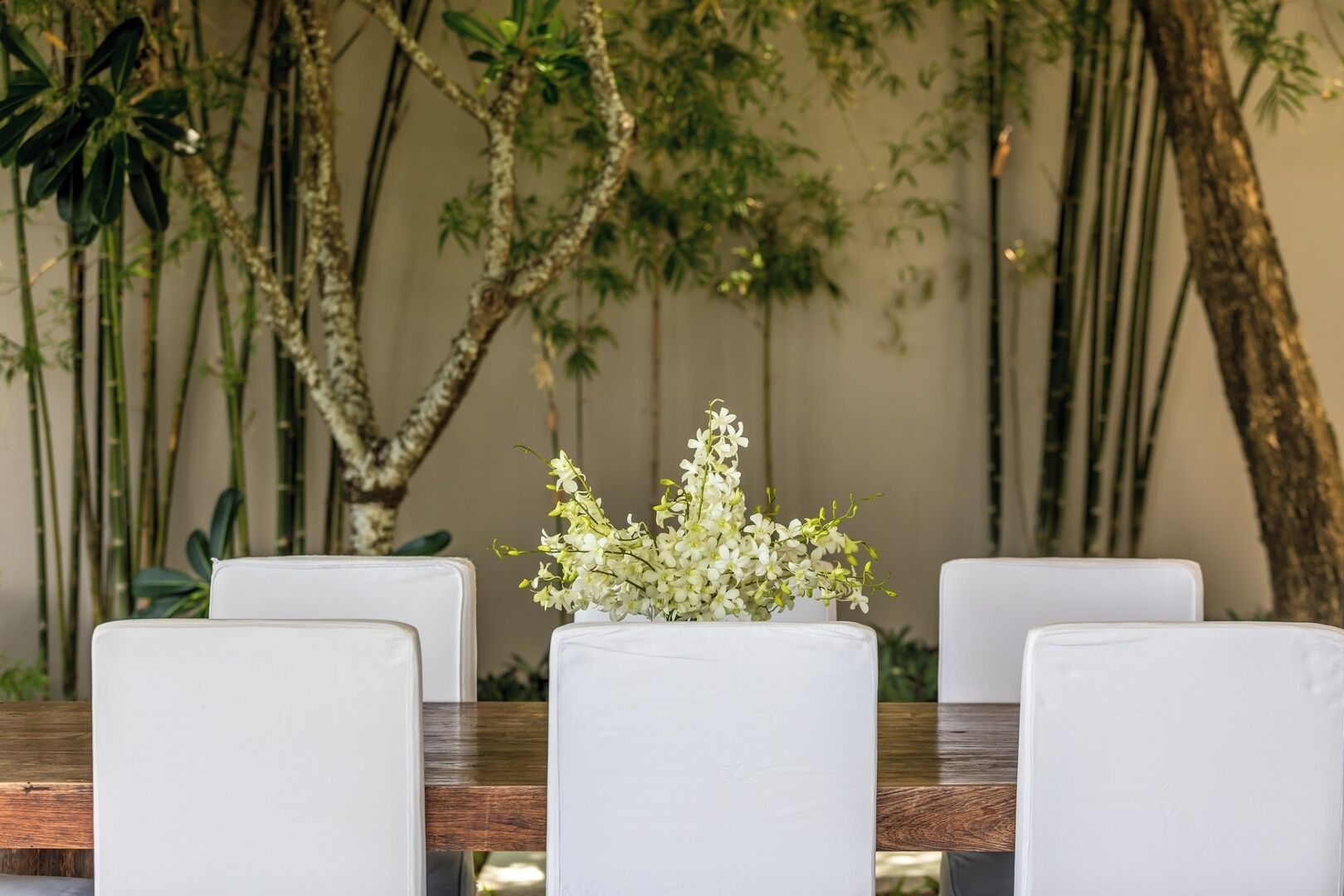 A dining table with white chairs and a floral centerpiece.