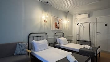 Habitación de hotel con dos camas individuales, un sofá, un espejo y un armario.