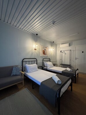 A hotel room with two single beds, a sofa, a mirror, and a wardrobe. - Siqui Pods (Siquijor)