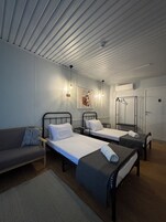 Habitación de hotel con dos camas individuales, un sofá, un espejo y un armario.