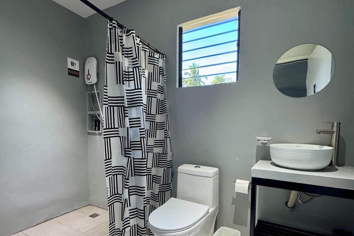 Un baño moderno con inodoro, lavamanos y cortina de ducha.