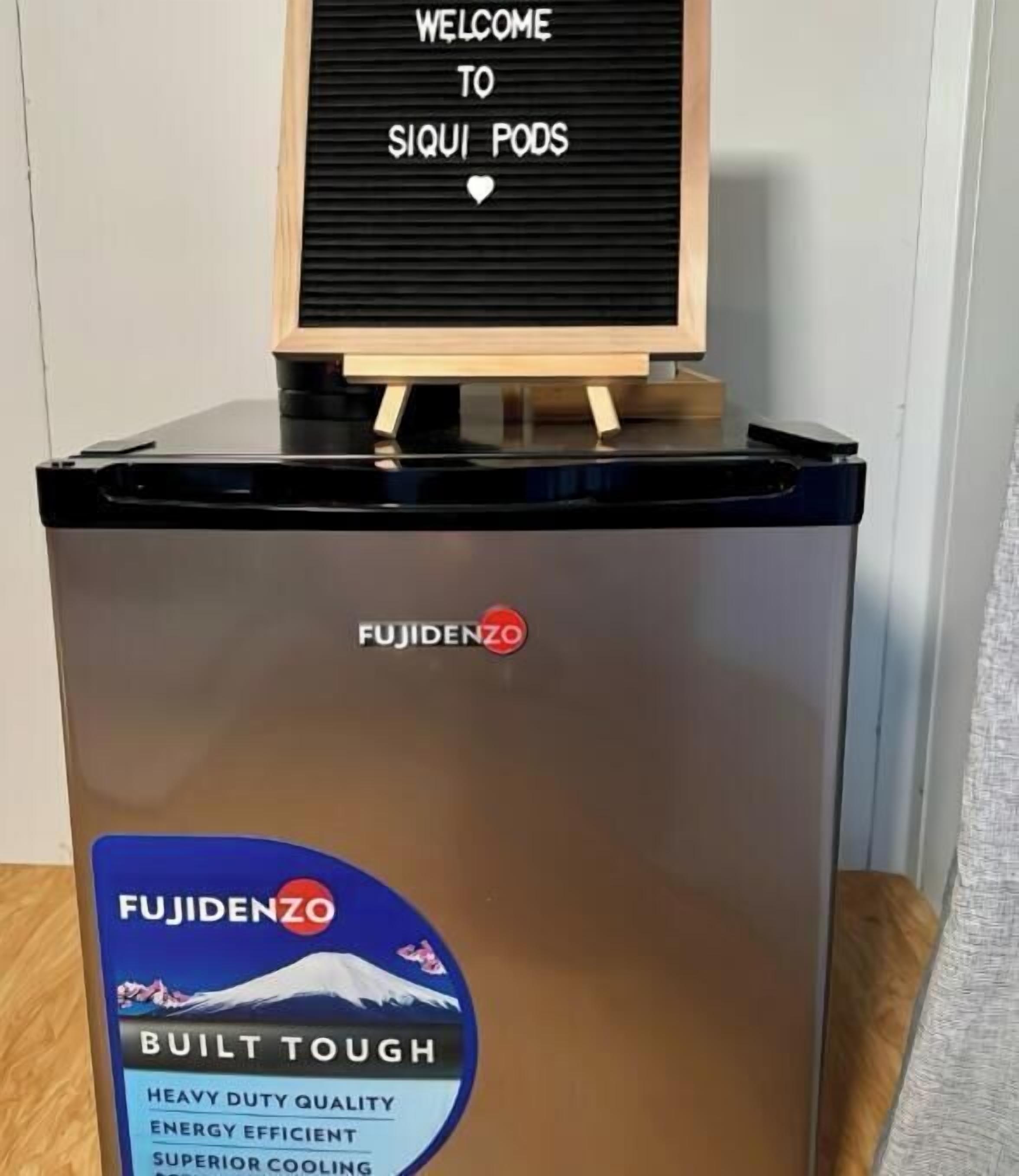A Fujidenzo refrigerator with a sign above it that reads "WELCOME TO SIQUI PODS".