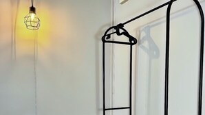 A room with a black metal shelf unit against a white wall, a small black table, and a hanging light fixture. - Siqui Pods (Siquijor)