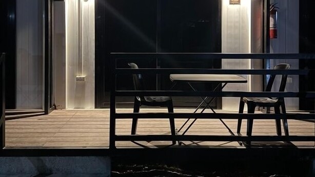 An outdoor patio area with a table and chairs, a covered entrance, and a door with a number '4' sign. - Siqui Pods (Siquijor)