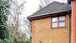 Una casa in mattoni con cornice rosso, un piccolo giardino e un vialetto lastricato che conduce all'ingresso.