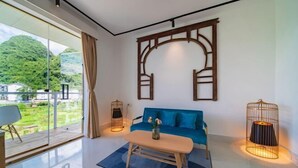 Una sala de estar moderna con un sofá azul, una mesa de centro de madera y un amplio ventanal con vistas a zonas verdes.
