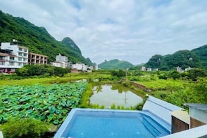 Vista de un hotel con piscina, rodeado de exuberante vegetación y colinas.