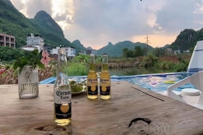 A wooden table with three Corona Extra beer bottles and a glass jar with flowers. - Yangshuo Liulianjian Homestay (Yangshuo)