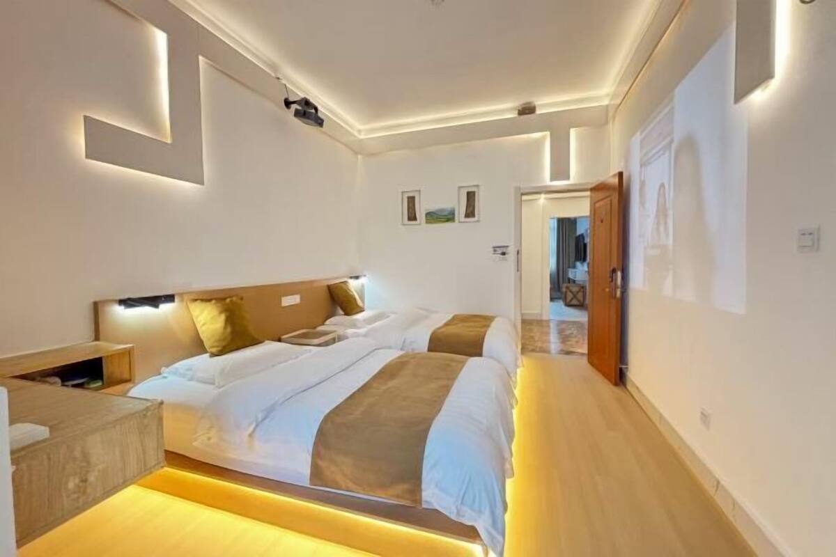 Una habitación de hotel moderna con una cama grande, mesitas de noche y un banco de madera.