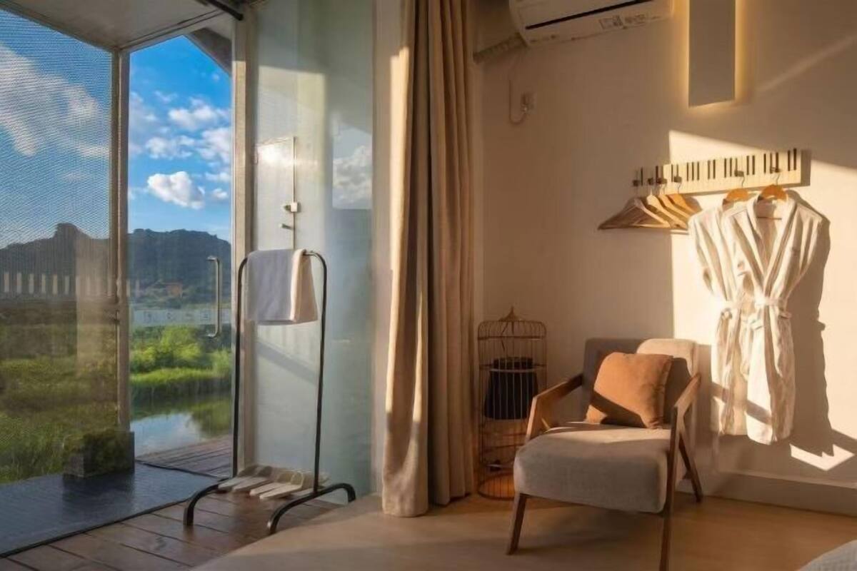 Una habitación con un ventanal grande, una silla, una bata y un perchero.