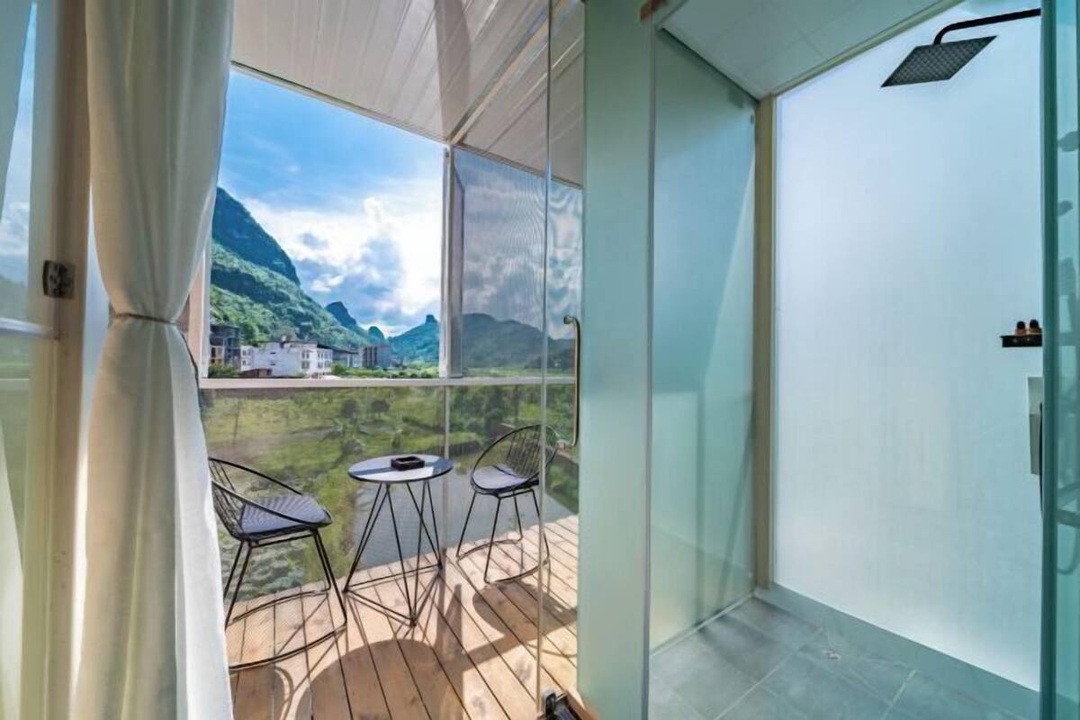 Un balcón con vistas a montañas, una puerta de cristal y una zona de ducha.