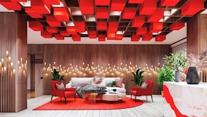 Una sala de estar moderna con suelo de madera, un sofá rojo, dos sillones rojos, una mesa de centro y un mostrador de recepción.