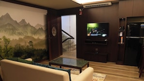 Una sala de estar con un sofá, una mesa de centro, un televisor y un refrigerador.
