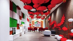 Un interior moderno con una zona de recepción, detalles decorativos rojo y blanco, y un logotipo en la pared.