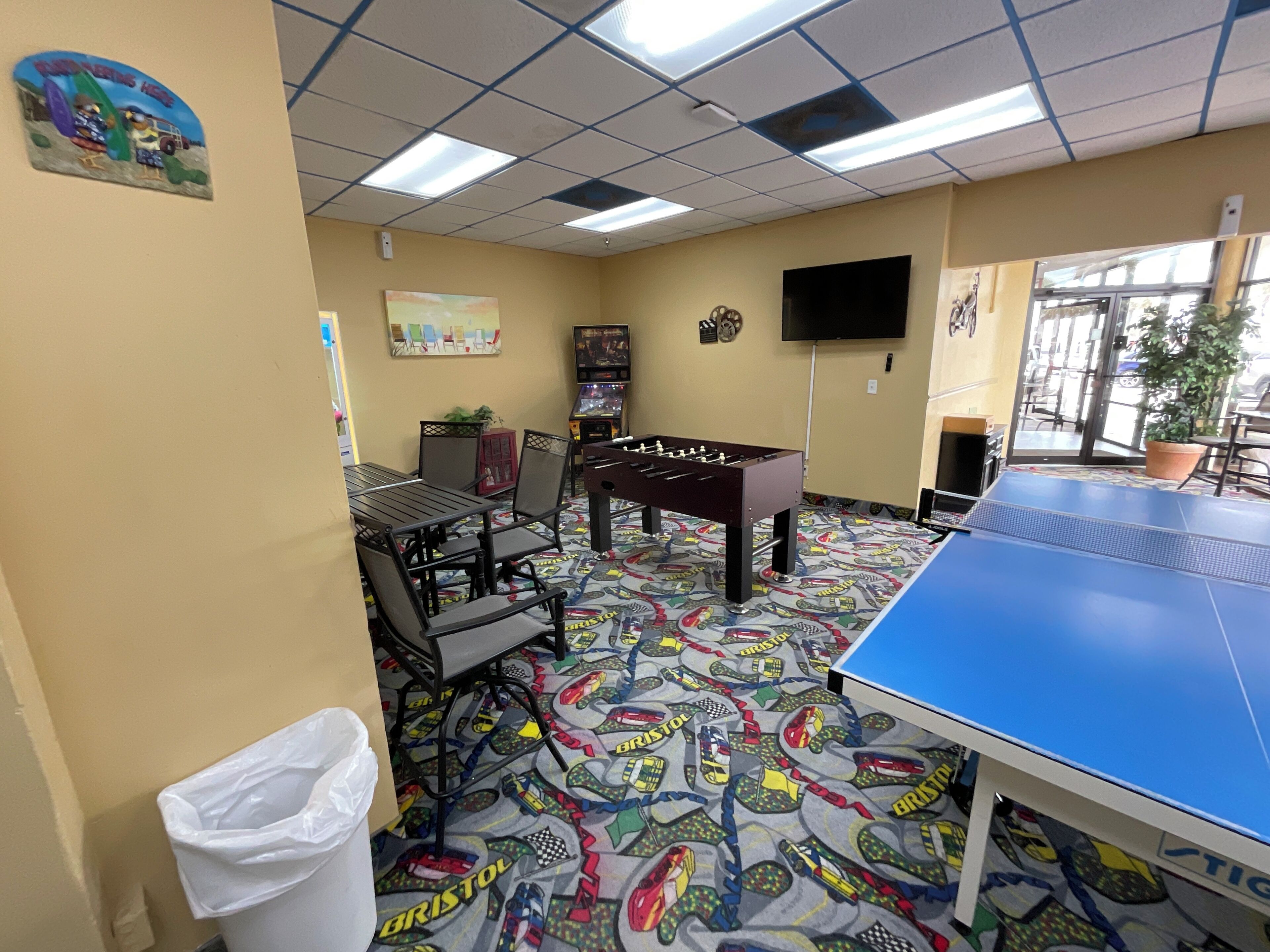 Une pièce équipée d’un baby-foot, d’une table de ping-pong et d’un téléviseur fixé au mur.