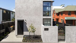 A modern two-story building with a concrete facade, large windows, and a small garden area. - Boutique Sophisticated One Bedroom Hideaway (Christchurch)