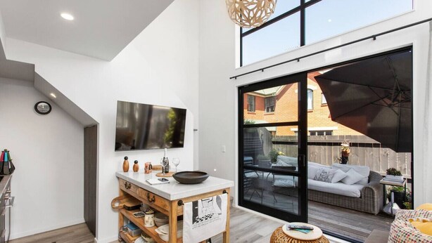 A modern kitchen with a large window, a dining area with a round table, and a cozy seating area with a wicker sofa and a patterned cushion. - Boutique Sophisticated One Bedroom Hideaway (Christchurch)