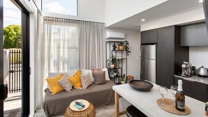 A modern kitchen with a built-in oven and a dining area with a table and chairs. - Boutique Sophisticated One Bedroom Hideaway (Christchurch)