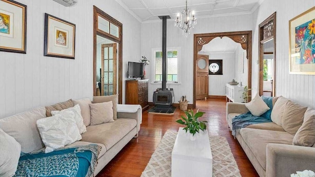 A cozy living room with two sofas, a coffee table, and a fireplace. - 3br Queenslander, close to city, transport and shops (Cannon Hill)