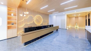 A modern reception area with a wooden slatted ceiling, a marble reception desk, and a wall with circular light fixtures. - Sanya Coconut Dream Corri RenJoy Hotel (Sanya)