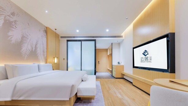 A modern hotel room with a large bed, a TV mounted on the wall, and a wooden floor. - Sanya Coconut Dream Corri RenJoy Hotel (Sanya)